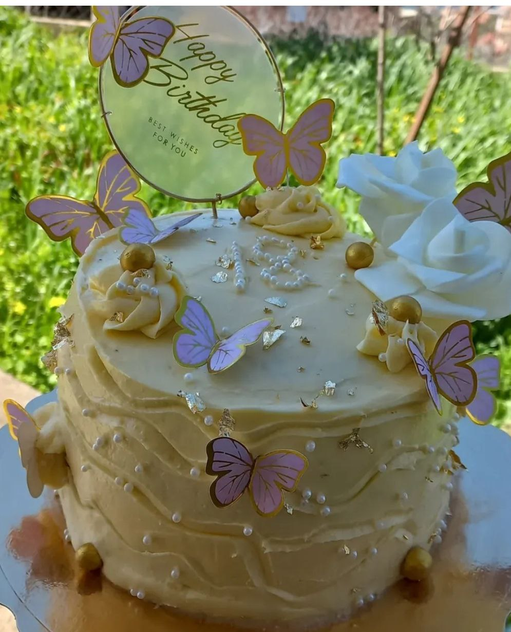 Gâteau d'anniversaire décoré de papillons violets et roses blanches